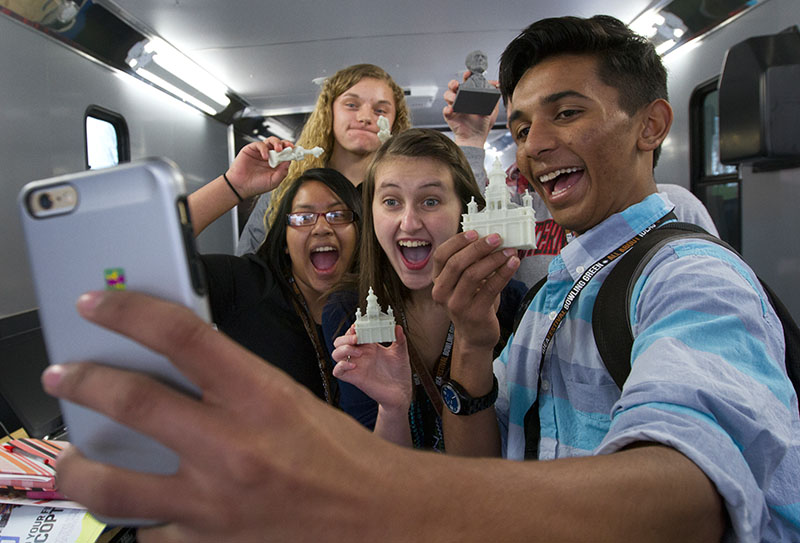 A group of IdeaFestival Bowling Green attendees pose for a selfie with items made by a 3D printer in the Maker Mobile.