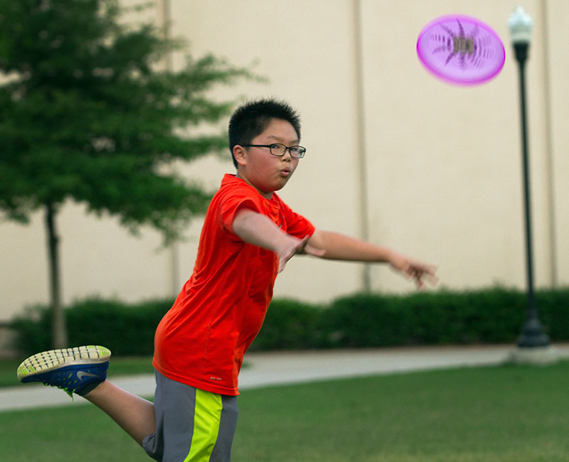Joshua Shou from Shanghai, China, tosses a frisbee to a fellow VAMPY camper during optionals Monday night on South Lawn. (Photo by Sam Oldenburg)