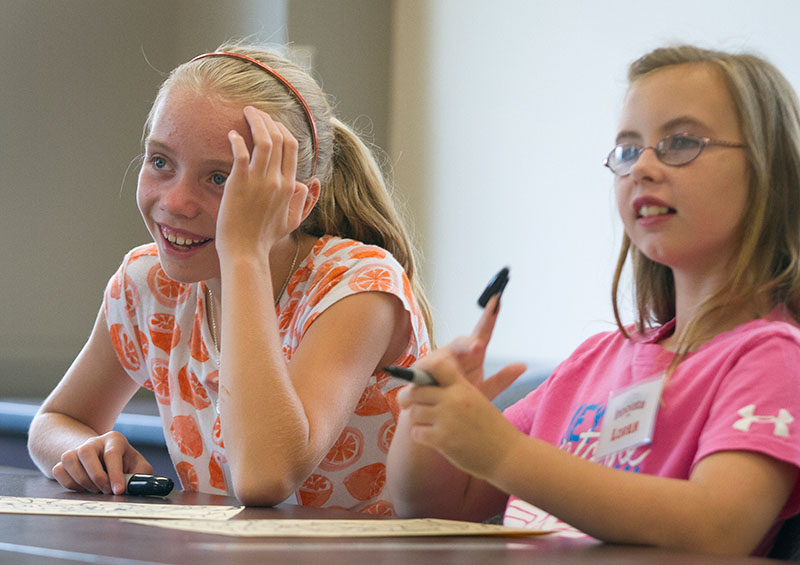 Sadie (left) and Loren listen to art teacher Andee Rudloff as she shows another student's artwork to the class on the first day of Camp Innovate Monday, June 29. (Photo by Sam Oldenburg)