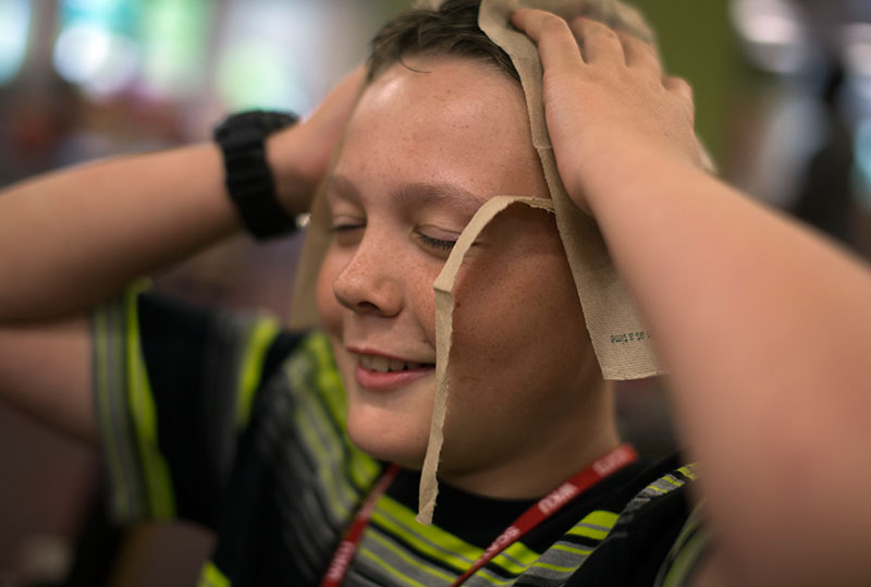 Cole LaDow of La Grange rips up napkins to make them into other things while waiting for other campers to finish dinner in Fresh Foods. All campers leave Downing Student Union together to return to Northeast Hall. (Photo by Emilie Milcarek)