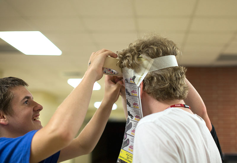 Trey Lang (left) of Waddy helps his teammate, Lij Brazel of Louisville, put on his costume for the Paper Theatre production Saturday, June 13. (Photo by Emilie Milcarek)