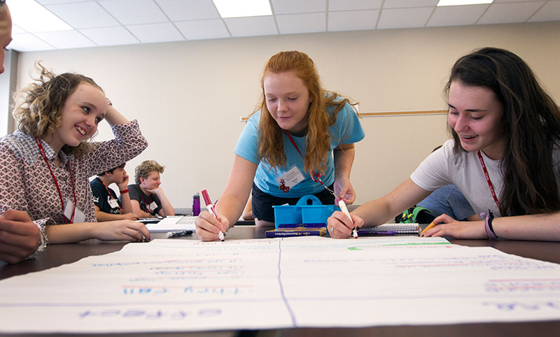 Rhiannon Wilson (from left) of Morgantown, Sarah Ball of Louisville and Maddie Holl of The Plains, Ohio, work as a group to brainstorm a list of causes and effects during The Roaring Twenties Tuesday, June 9. (Photo by Sam Oldenburg)