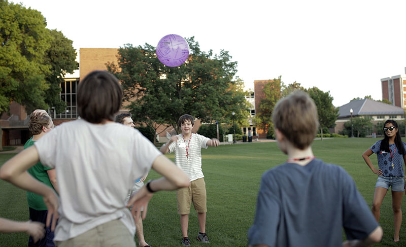 Caleb Cummings of Imperial, Mo., throws a ball to other campers during a get-to-know-you game on South Lawn. A variety of questions were written on the ball that campers had to answer when they caught it. (Photo by Emilie Milcarek)