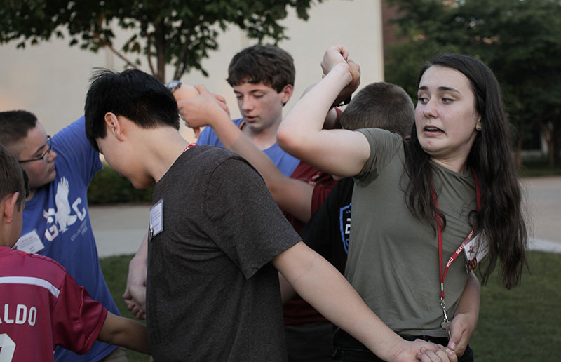 Maddie Holl tries to get out of a human knot with other campers as part of an ice breaker game on South Lawn  Sunday, June 7. (Photo by Emilie Milcarek)