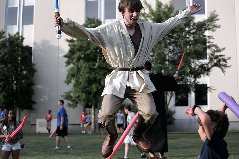 Counselor Ben Guthrie engages VAMPY campers during the optional, Jedi vs. Sith. Campers were taught special moves and fought each other with pool noodle light sabers on Wednesday, June 24, outside Grise Hall. (Photo by Emilie Milcarek)