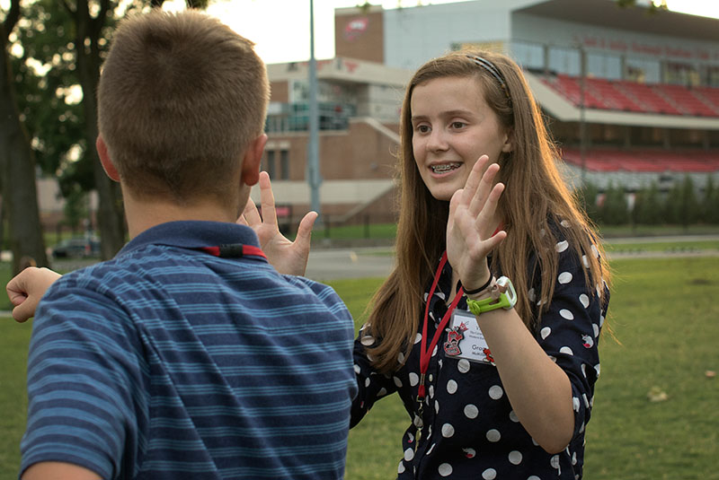Grace Mcmillin of Paris tries to silently tell her friend what month she was born so that her group can make a line from oldest to youngest during ice breakers on Sunday, June 21. (Photo by Emilie Milcarek)
