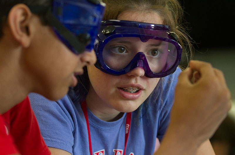 Anna Youngblood of Paducah looks at an element held by her lab partner, Milai Sheth of Brentwood, Tennessee, Wednesday, June 24, during Chemistry. Students examined attributes of a variety of elements in a chemical reactivity lab. (Photo by Sam Oldenburg)