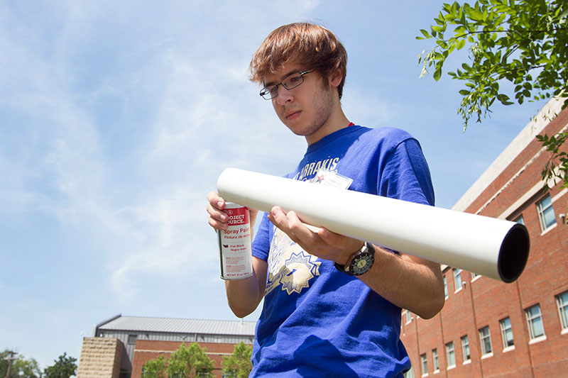 Kiernan Jolly of Louisville spray paints a piece of a telescope during Astronomy Wednesday, June 24. Students built their own telescopes and will use them to look at the night sky in the coming weeks. (Photo by Sam Oldenburg)