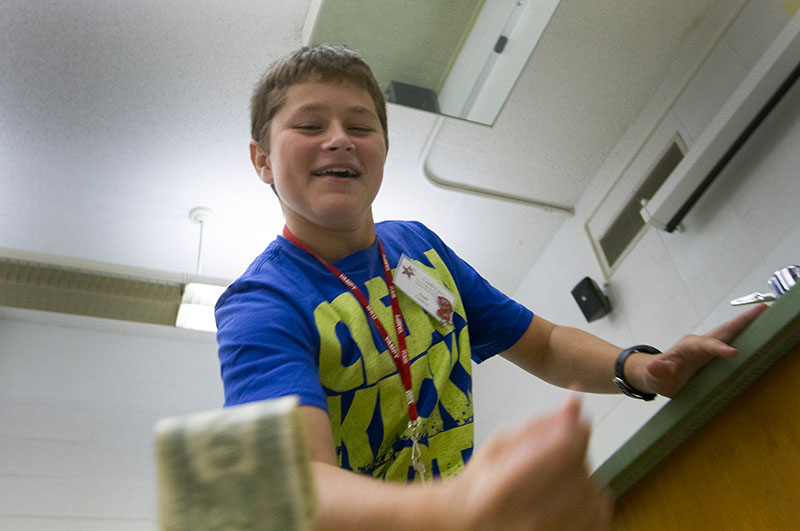 Josh Coleman of Maysville tries to grab a dollar bill dropped by Physics teacher Kenny Lee during a demonstration to test his reaction time Wednesday, June 24. (Photo by Sam Oldenburg)