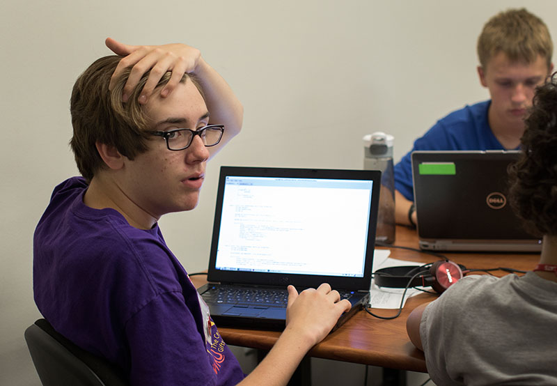 Christian Lauritzen of Lexington asks his teacher for help while working on his coding project in Computer Science Thursday, July 9. (Photo by Emilie Milcarek)