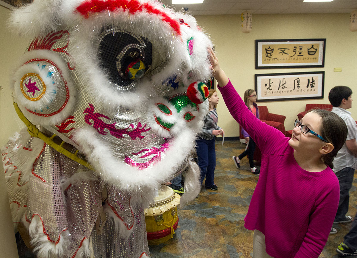 Hallie Miles examines a lion dance costume while touring the Chinese Learning Center presented by the Confucius Institute in Helm Library with her class, Create Your Own Chinese Masterpiece.