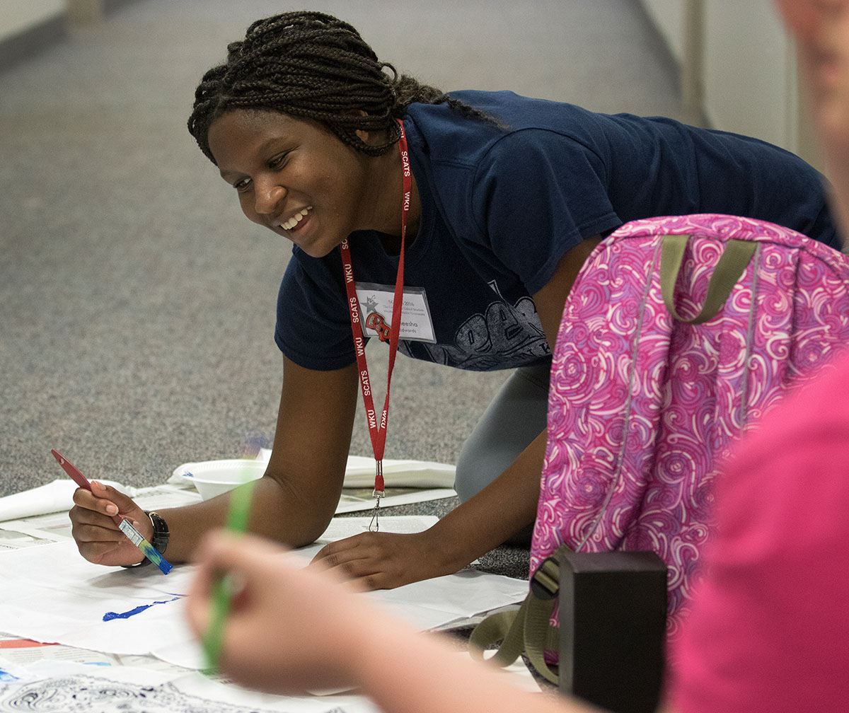 Aneesha Edwards of Lexington paints a bandana alongside other campers in her counselor group during hall time Thursday, June 16. The girls were painting the bandanas in preparation for SCATS Olympics, where their group will represent Atlantis. (Photo by Sam Oldenburg)