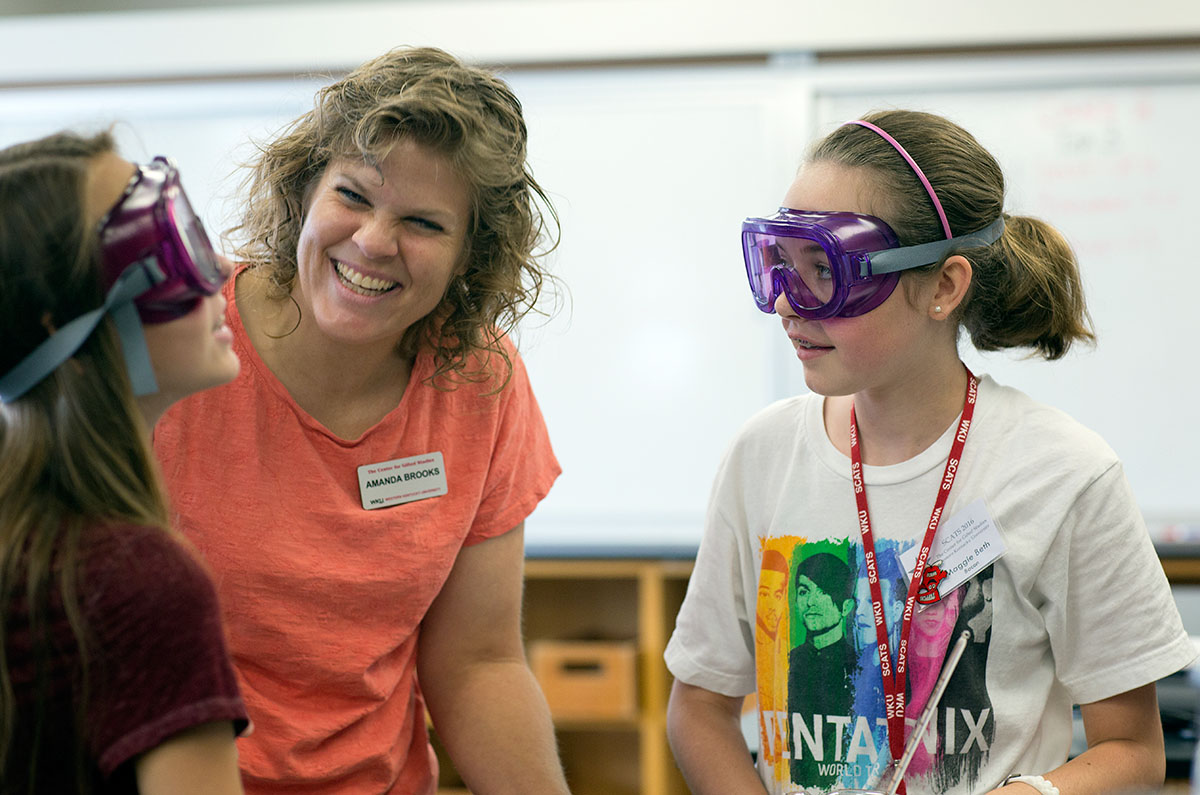 Breanne Davis (left) from Knoxville, Tennessee, and  Maggie-Beth Bacon from Owensboro receive light-hearted instruction from hemistry of Everyday teacher Amanda Brooks Friday, June 17. Students mixed purified water, rock salt, and ice to see the effects of ice on the freezing point of water then used the same process to make ice cream. (Photo by Tucker Allen Covey)