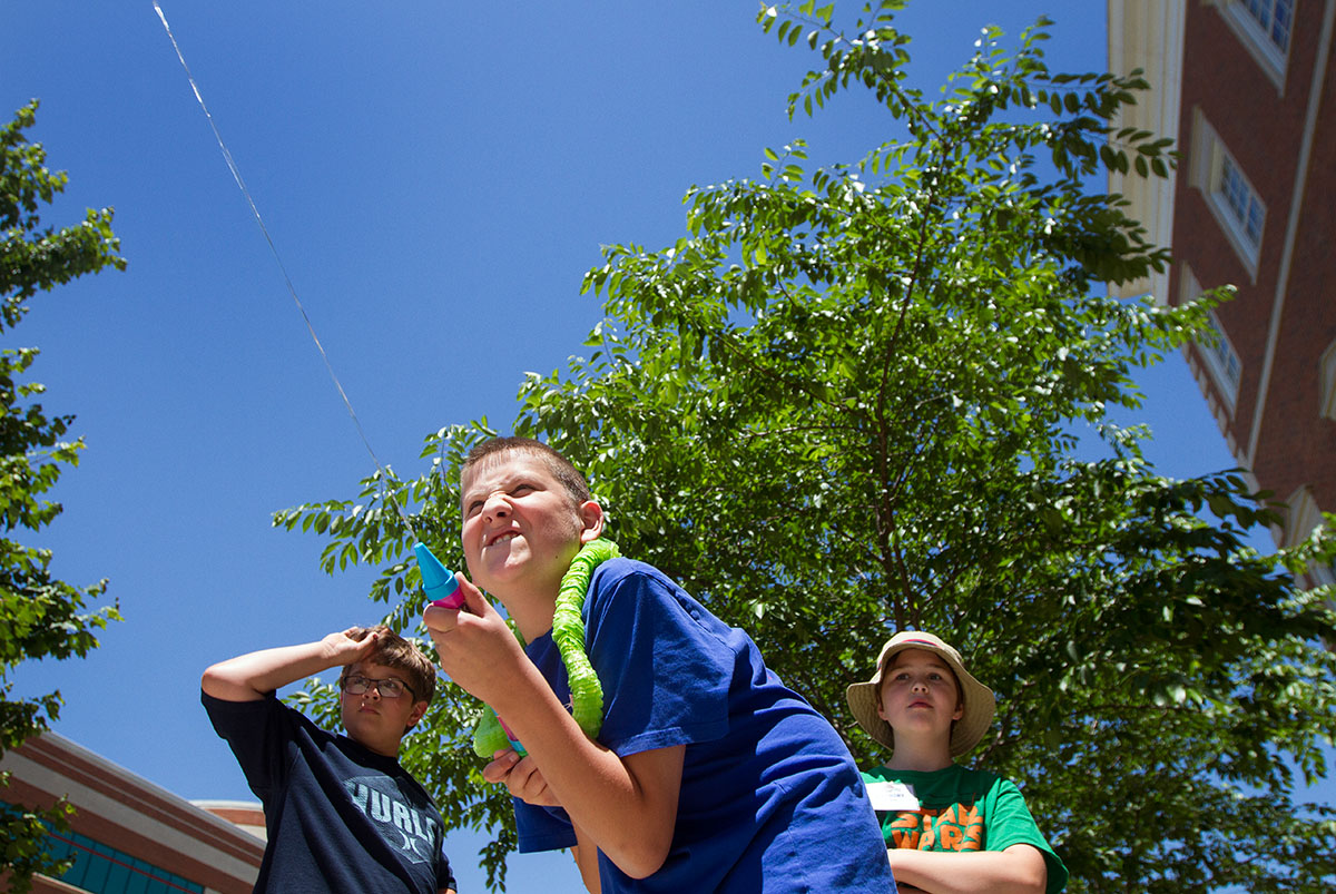 Destry Miller squirts a water launcher as his group members Christian Kantosky (left) and Anthony Counts watch during Math at Camp Innovate Monday, June 6. The students used various water tools and took measurements to find which sent water the furthest. (Photo by Sam Oldenburg)