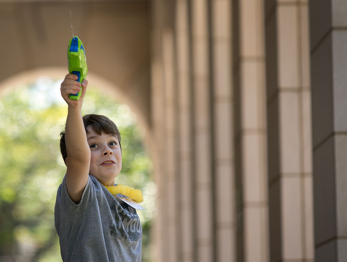 Elijah Bemiss stretches his arm to make water go further while squirting a water gun during Math at Camp Innovate Monday, June 6. The students used various water tools and took measurements to find which sent water the furthest. (Photo by Sam Oldenburg)