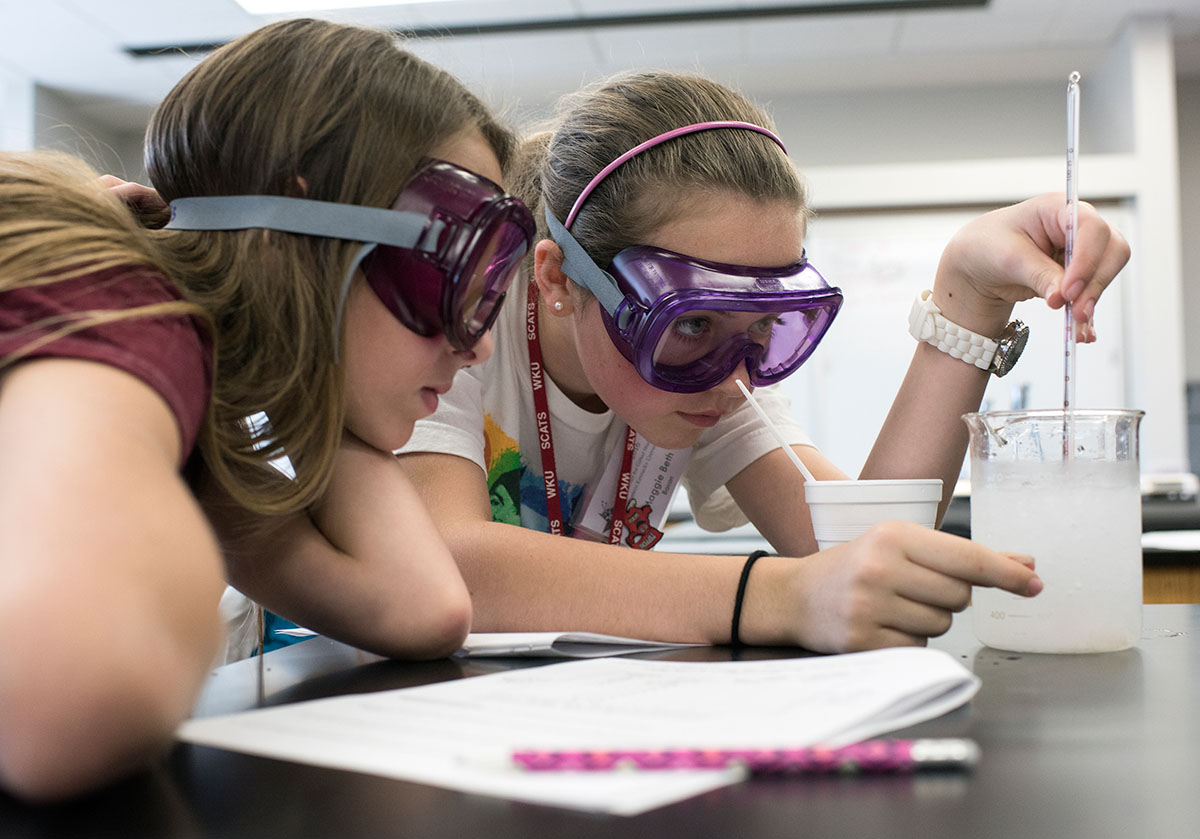 Breanne Davis (left) from Knoxville, Tennessee, and Maggie-Beth Bacon from Owensboro measure the temperature of ice water with salt mixed in to explore how salt lowers the freezing point of ice during Chemistry of Everyday Friday, June 17. (Photo by Tucker Allen Covey)