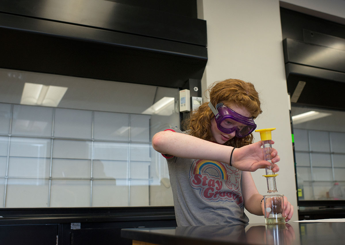 Taylor Galavotti from Lexington carefully adds vegetable oil into a beaker to be stirred and mixed with scented oils to make soap during Chemistry of Everyday Wednesday, June 22. (Photo by Tucker Allen Covey)