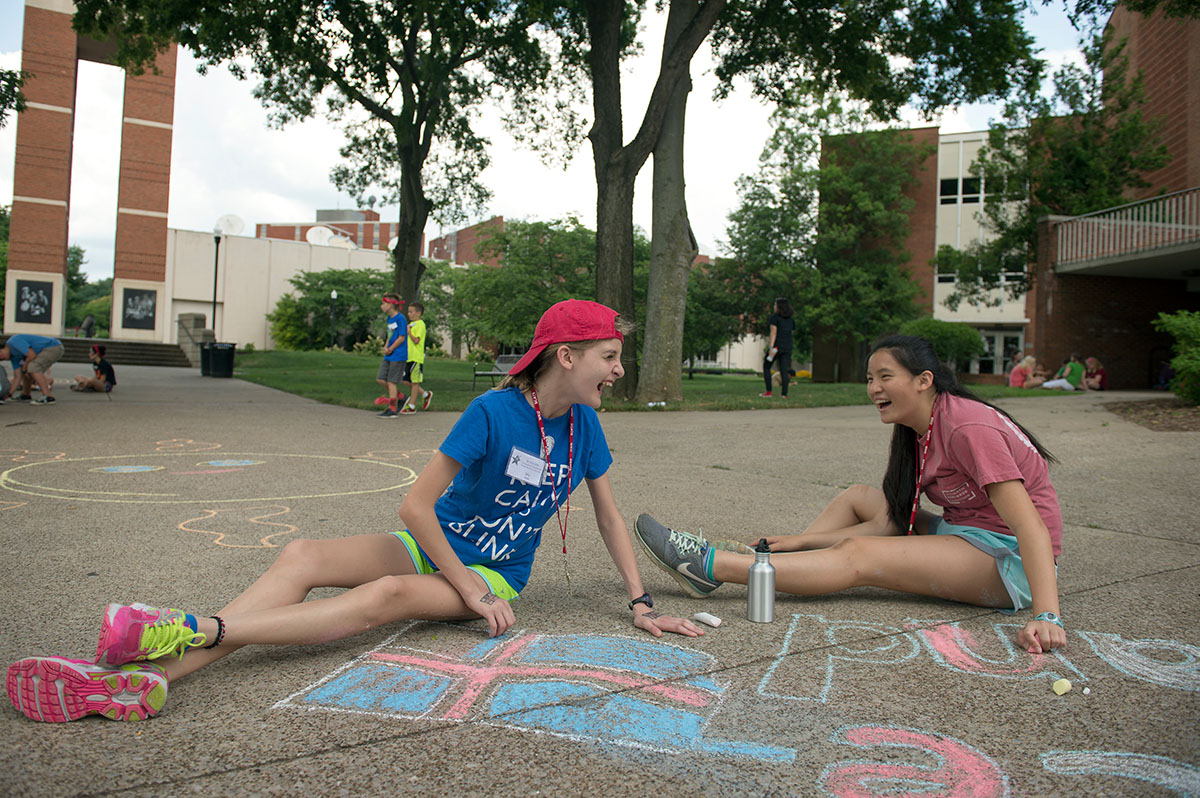 Lily Jones (left) from Cincinnati, Ohio, and Lia Anderson from Louisville stay cool in the shade drawing with chalk during the SCATS Olympics Saturday, June 18. (Photo by Tucker Allen Covey)