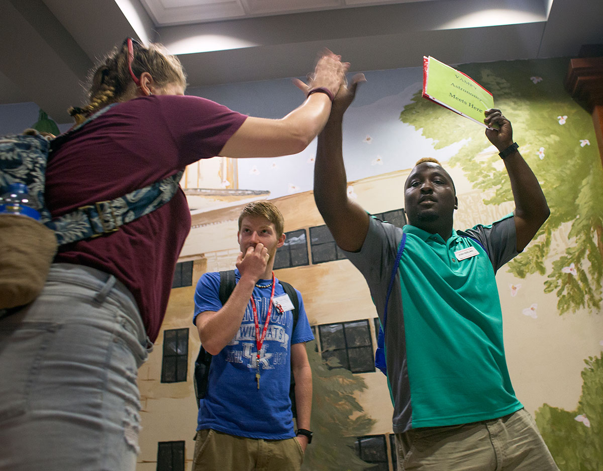 Astronomy teaching assistant Josh Keeling exchanges a high-five with a student as they prepare to go to class after breakfast Monday, June 27. (Photo by Tucker Allen Covey)