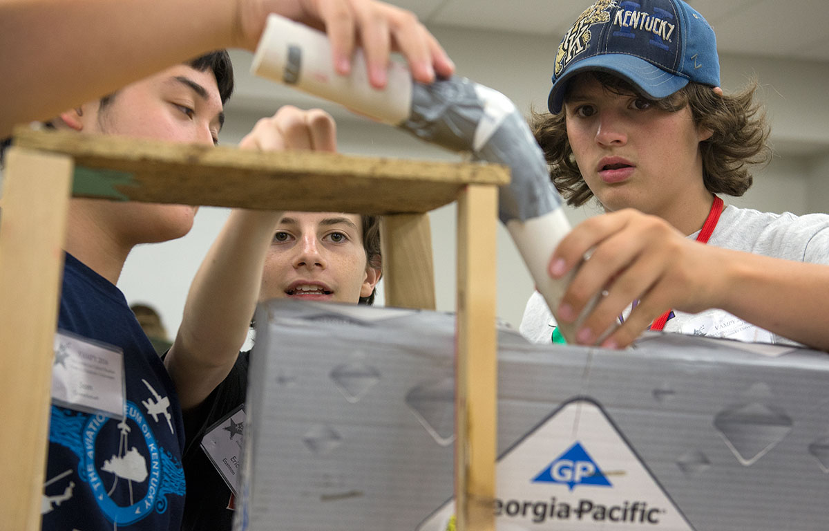 Sam Greenbaum (from left) of Louisville, Eric Eastman of Bowling Green, and Zach Hanvey of Paris, Kentucky, work to build the second step of their Rube Goldberg Machine in STEAM Labs on Thursday, June 30. (Photo by Tucker Allen Covey)