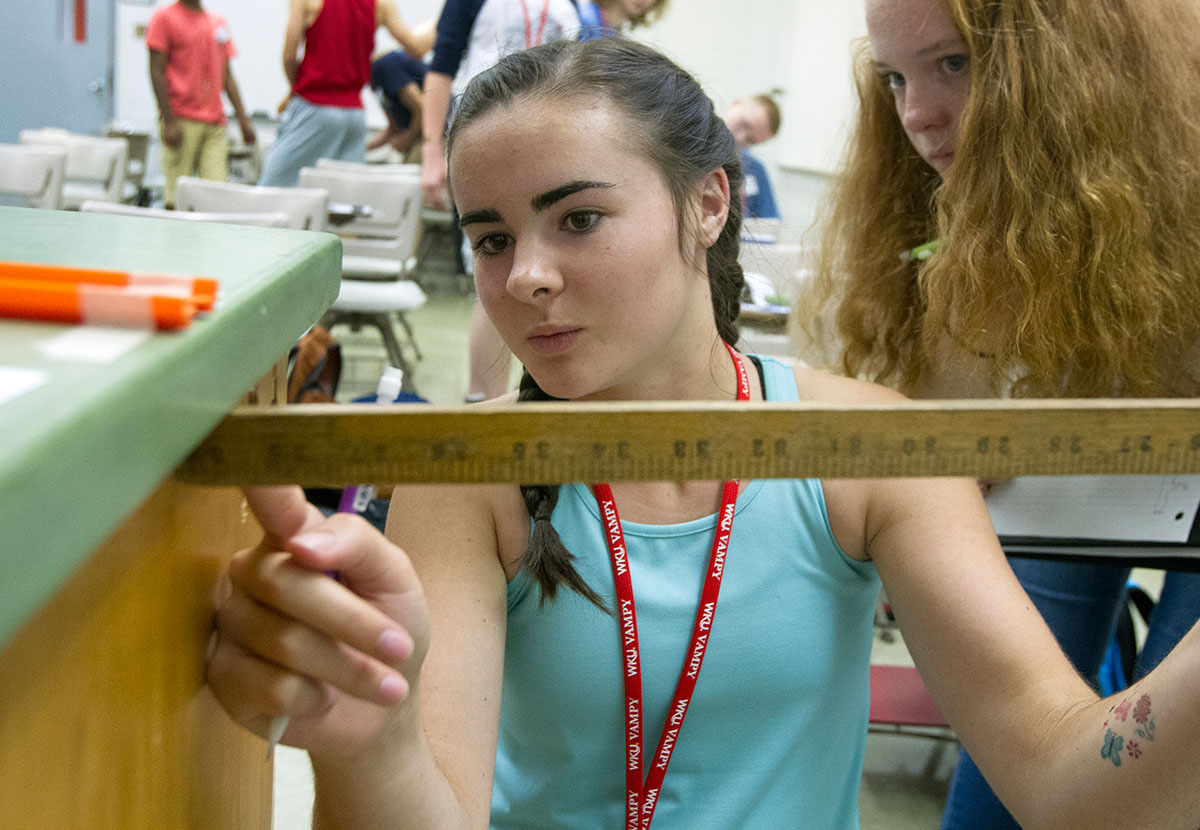 Susanna Moore of Junction City while her partner Anna Duncan of Chattanooga, Tennessee, watches during Physics Wednesday, June 29. The students were learning how to calculate the velocity of a projectile using a ball bearing and a Hot Wheels ramp. (Photo by Sam Oldenburg)