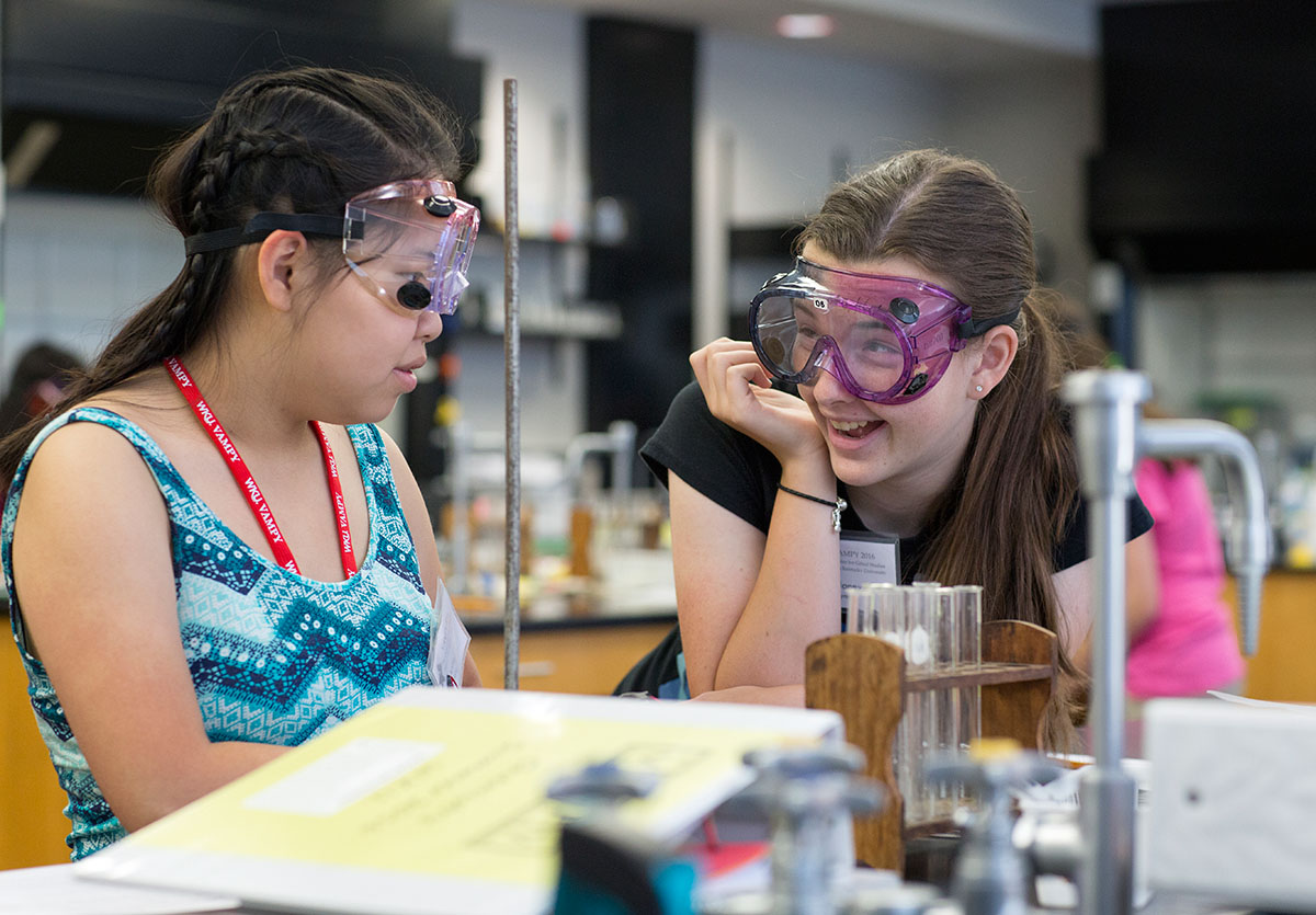 Anna Dong (left) from Morganfield and Delaney Bynum from Hopkinsville react during a lab in Chemistry Thursday, June 30. The students used used an electrical current to change the color of a solution. (Photo by Tucker Allen Covey)