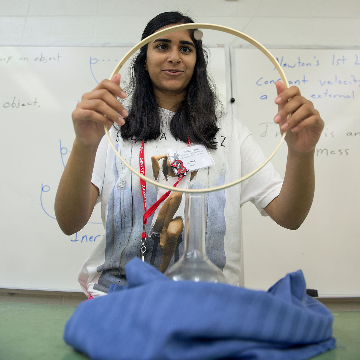 Ruthie Kesri from Bowling Green attempts to drop a coin from the ring she is holding into the flask beneath during Physics Thursday, June 30. The task demonstrated that momentum and inertia are far more difficult to overcome than the students originally thought. (Photo by Tucker Allen Covey)