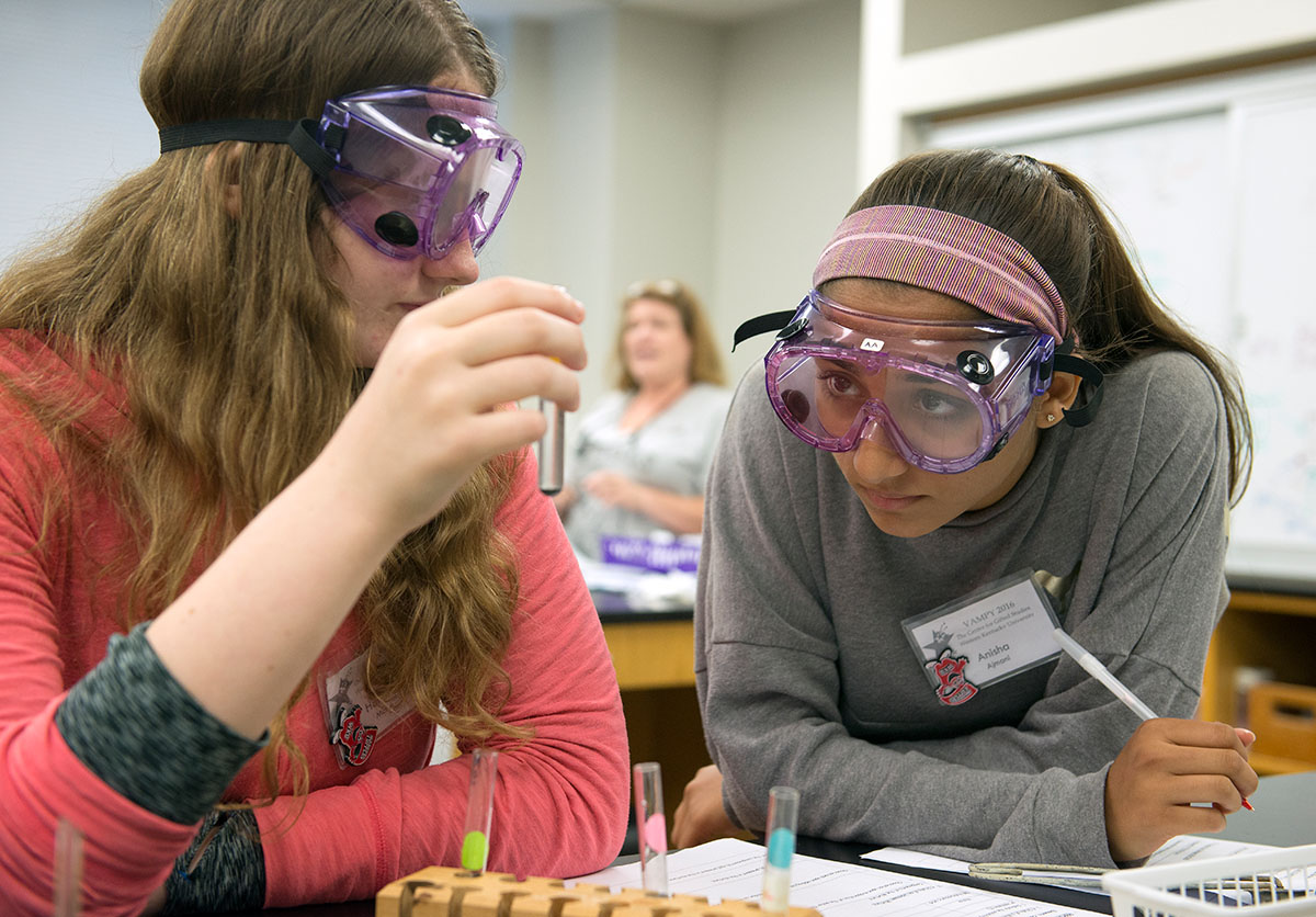 Hannah Motes (left) from Clarksville, Tennessee, and Anisha Ajmani from Goshen observe the solution of magnesium and an acid they put together in Chemistry before exposing the solution to heat on Wednesday, July 6. (Photo by Tucker Allen Covey)