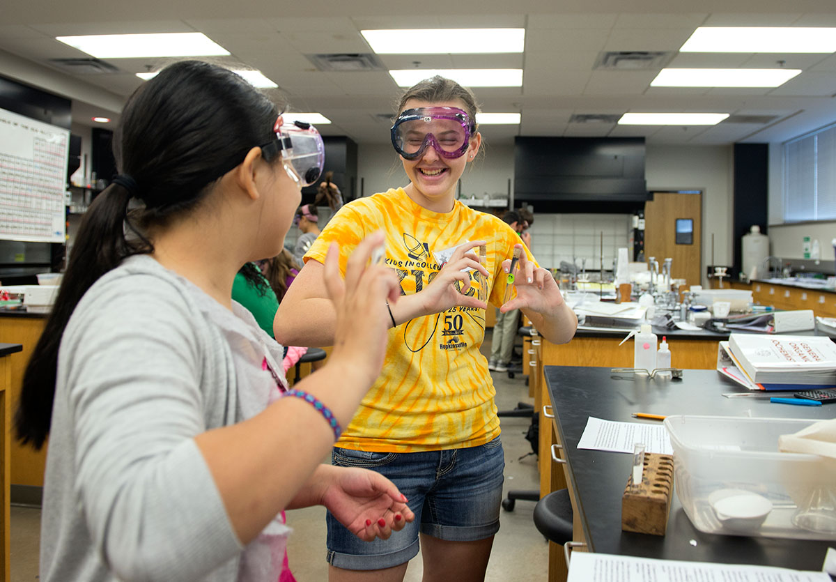 Anna Dong (left) from Morganfield and Delaney Bynum from Hopkinsville shake up the solutions they created in Chemistry shortly before exposing a cleaned version of the solutions to heat on a bunsen burner Wednesday, July 6. (Photo by Tucker Allen Covey)