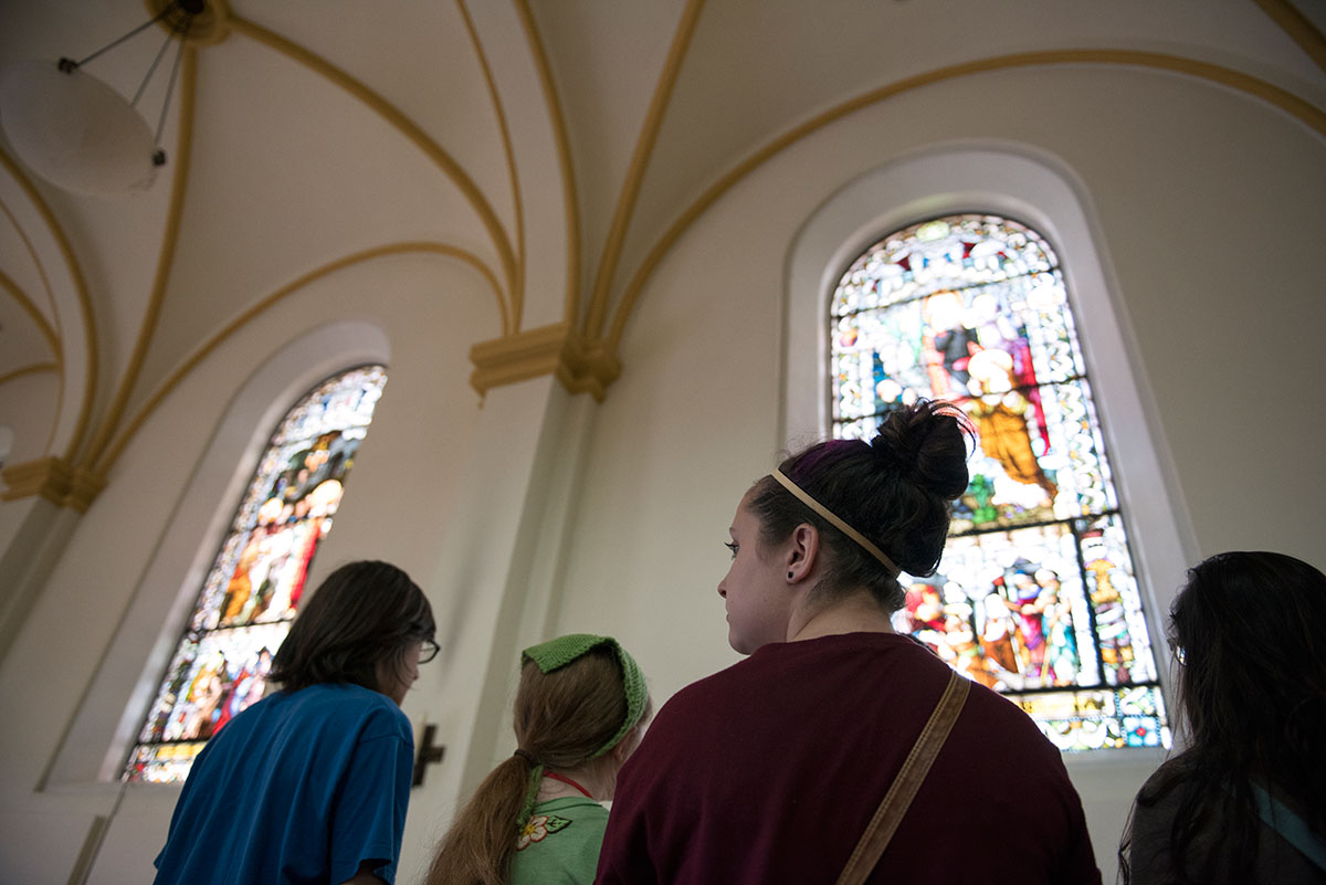 Rhianna Clemons of Elizabethtown and her classmates in Humanities admire the stained glass windows inside the Archabbey Church at Saint Meinrad Archabbey in Saint Meinrad, Indiana, Tuesday, July 5. The students learned about the lives of the monks as well as the artwork adorning the Catholic monastery. (Photo by Tucker Allen Covey)