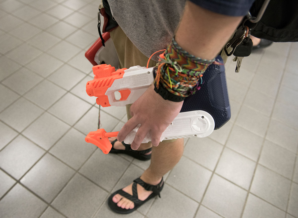 With a friendship-bracelet clad arm, counselor Jacob Couch grips his water gun, which he uses to keep order in the seimming pool, at the Preston Center Friday, July 1. (Photo by Tucker Allen Covey)