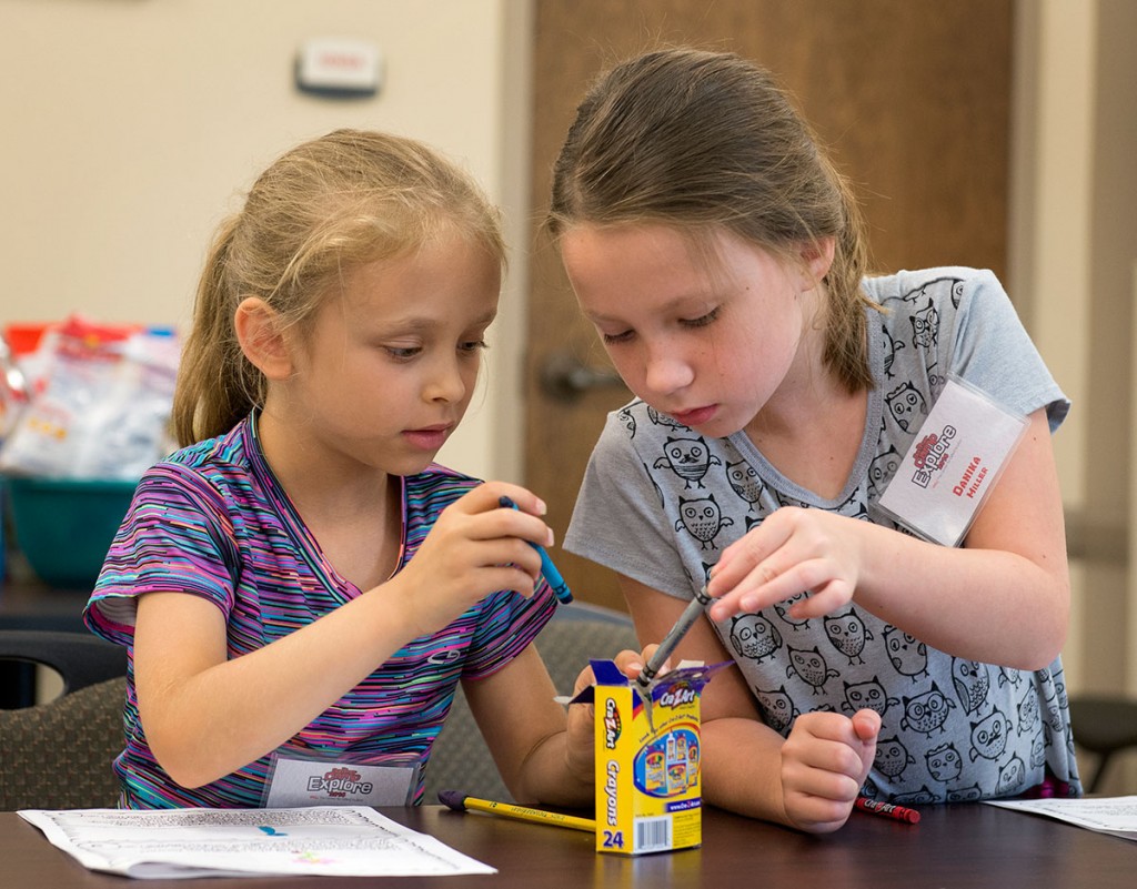 Stella Miner (left) and Danika Miller work together to color the animals in a food chain during Science Monday, July 11. (Photo by Tucker Allen Covey)