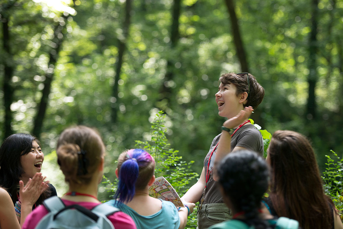 Zoe Ward (center) from Frankfort reads poetry to her Writing classmates while perched on a stump during on a field trip to Lost River Cave in Bowling Green Thursday, July 14. (Photo by Tucker Allen Covey)