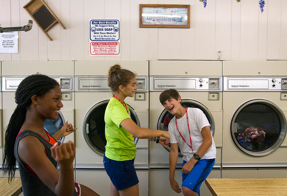 Jocelyn Martin (from left) of Russell and Maya Abul-Khoudoud of Ashlandteach a dance to Grant Coorssen of Louisville while waiting for their clothes to dry at Bryce's Bypass Laundromat Sunday, July 10. (Photo by Sam Oldenburg)