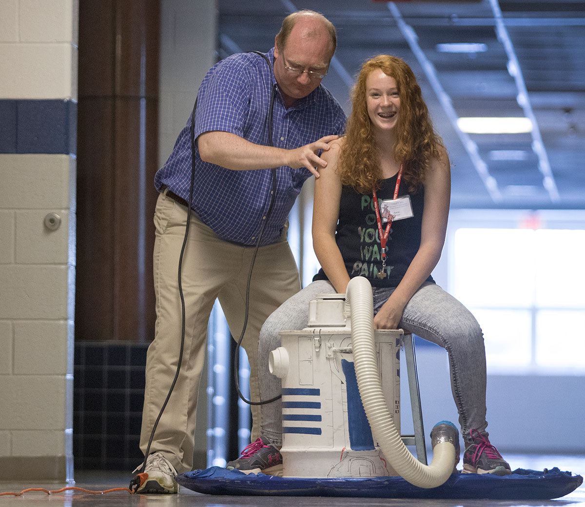 Physics teacher Kenny Lee prepares to push Anna Duncan from Chattanooga, Tenn., on a hovercraft down a hallway at Warren Central High School, where Kenny teachers, during a class trip Wednesday, July 13. (Photo by Sam Oldenburg)