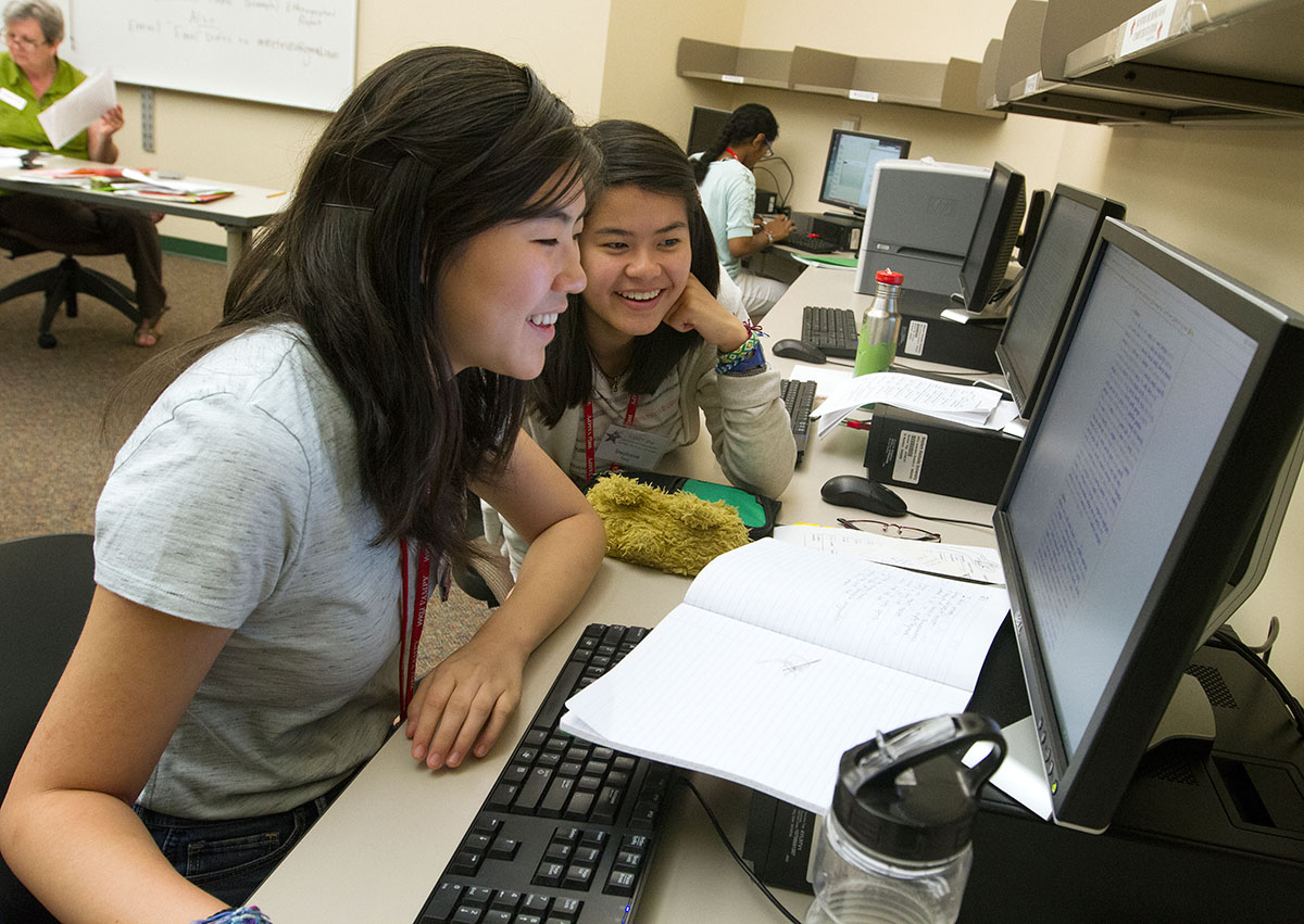 Megan Guan (left) and Stephanie Yang, both of Lexington, look up rhyming words for Megan's poem in Writing Wednesday, July 13. (Photo by Sam Oldenburg)