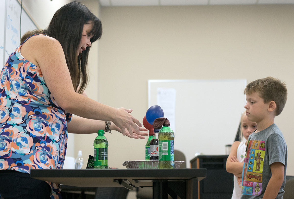Ben Brown watches as Math teacher Allison Bemiss mixes soda and Pop Rocks for an experiment Tuesday, June 6. Bemiss combined math and science to teach her class about chemical reactions and measuring 3-D objects. (Photo by Brook Joyner.)