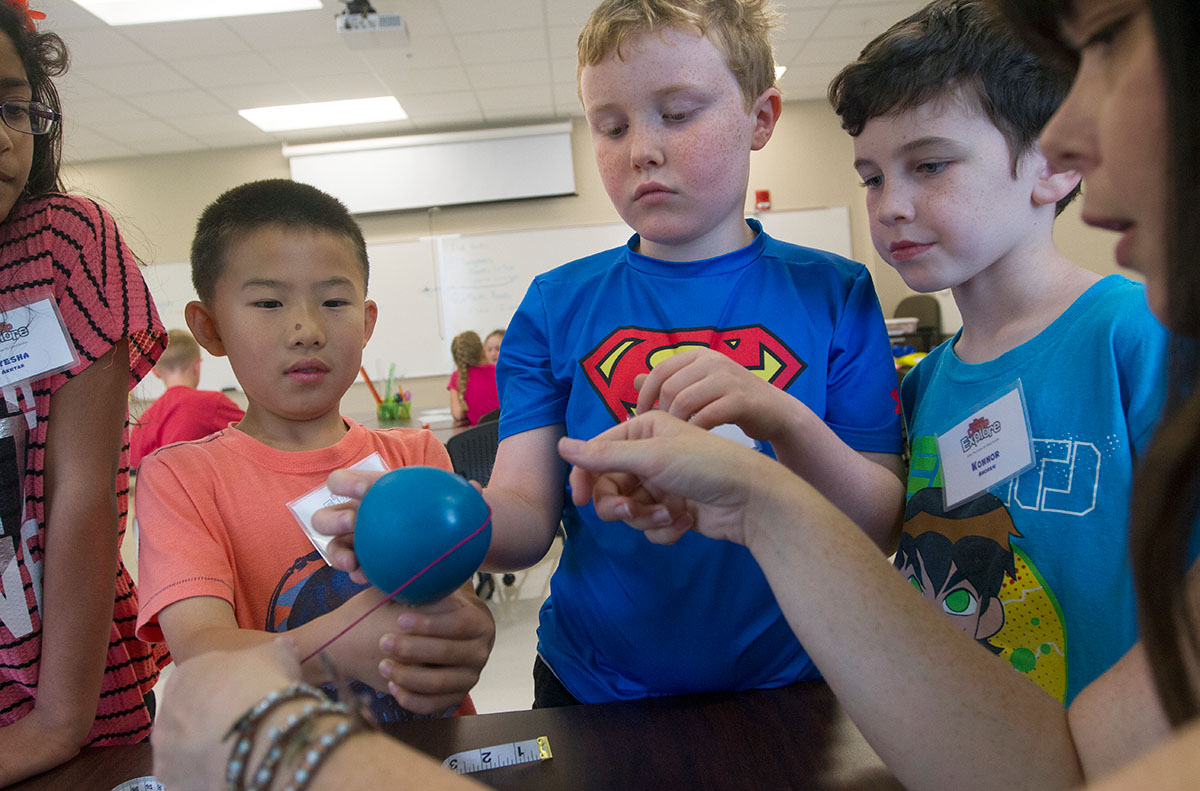 Kenny Chen (from left), Henry Hulan, and Konnor Andrew measure the circumference of a balloon filled with carbon dioxide from a bottle of Sprite Tuesday, June 6 during Math at Camp Explore (Photo by Sam Oldenburg)