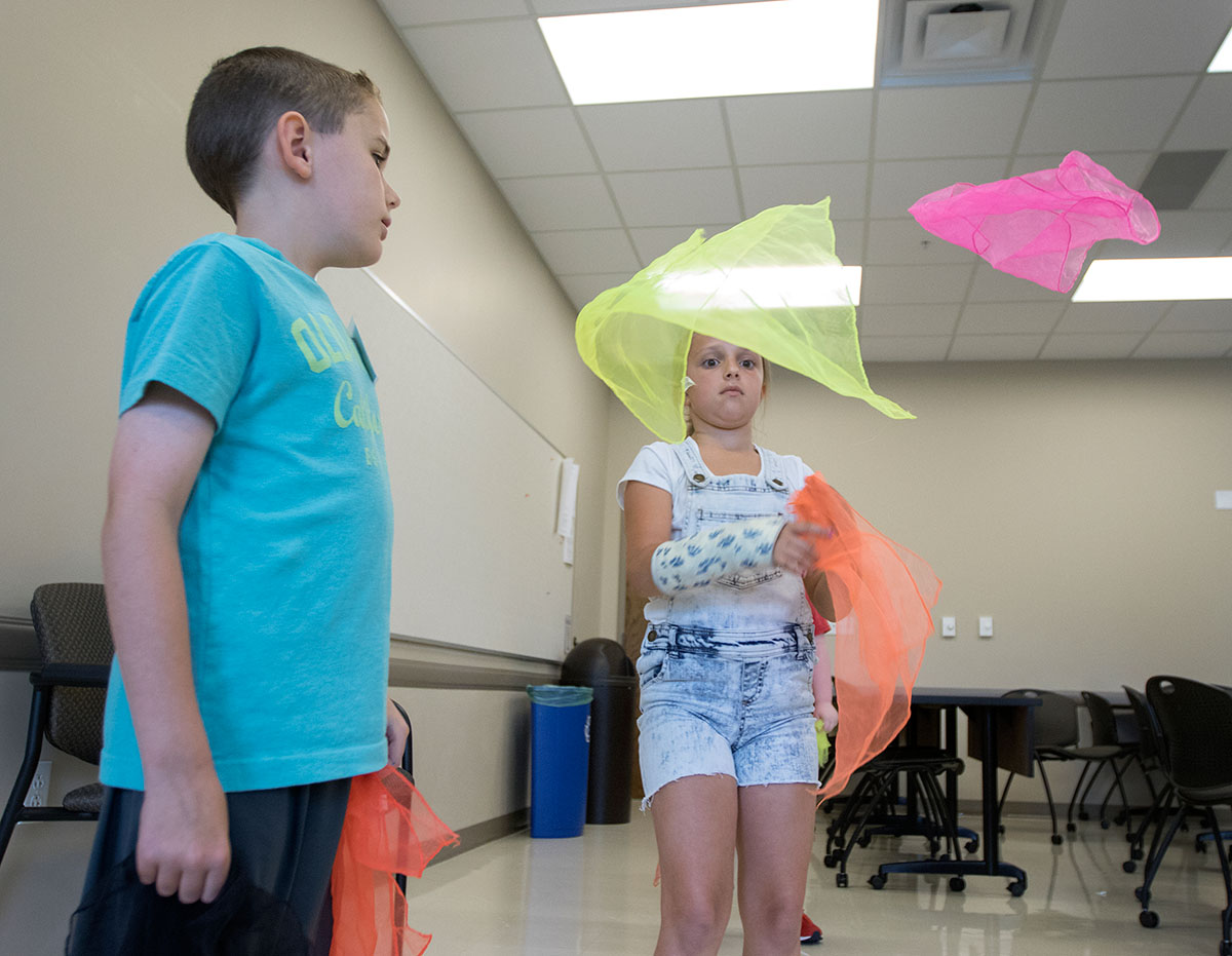 Braydon Thompson (left) and Caroline Powers practice juggling during Clowning on Tuesday, June 6. The students started with scarves before attempting to juggle with balls. (Photo by Brook Joyner)