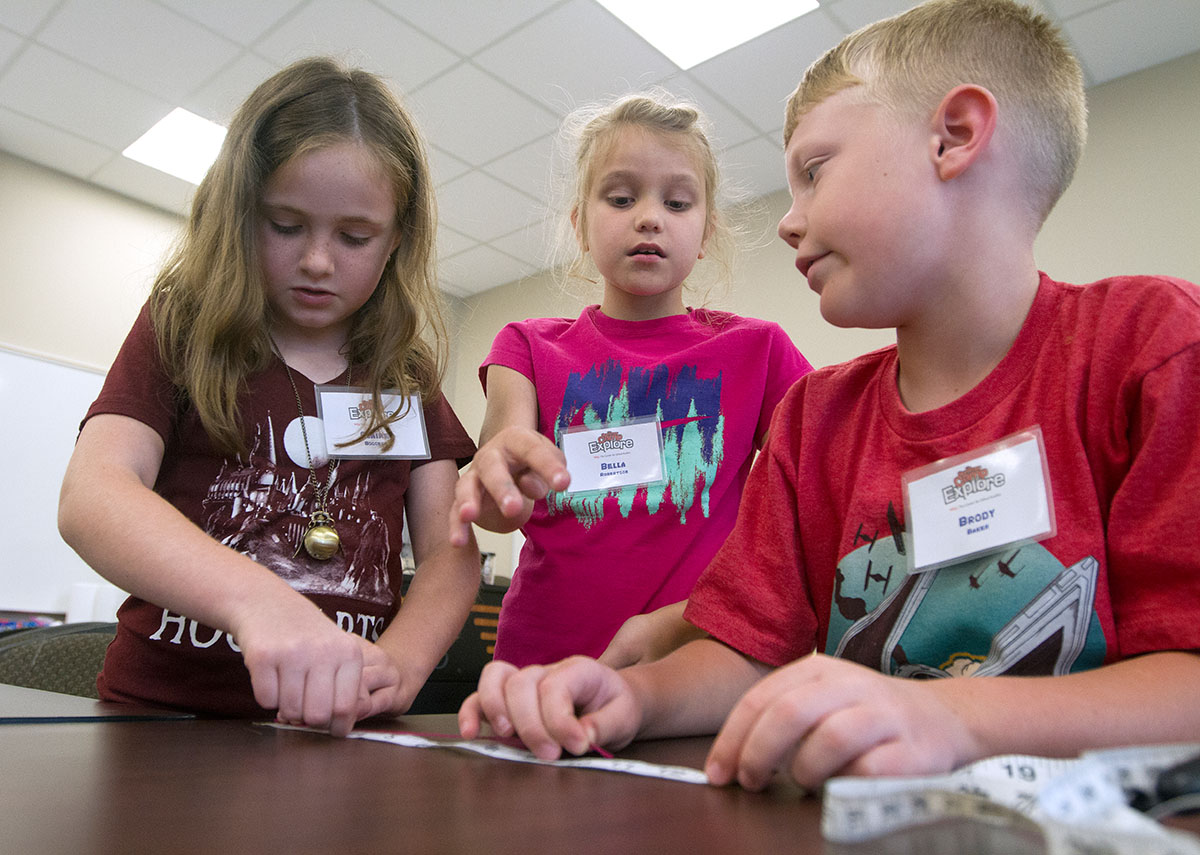 Claire Boggess (from left), Bella Robertson, and Brody Baker measure a string they used to calculate the circumference of a balloon filled with carbon dioxide from Diet Coke Tuesday, June 6 during Math at Camp Explore. (Photo by Sam Oldenburg)