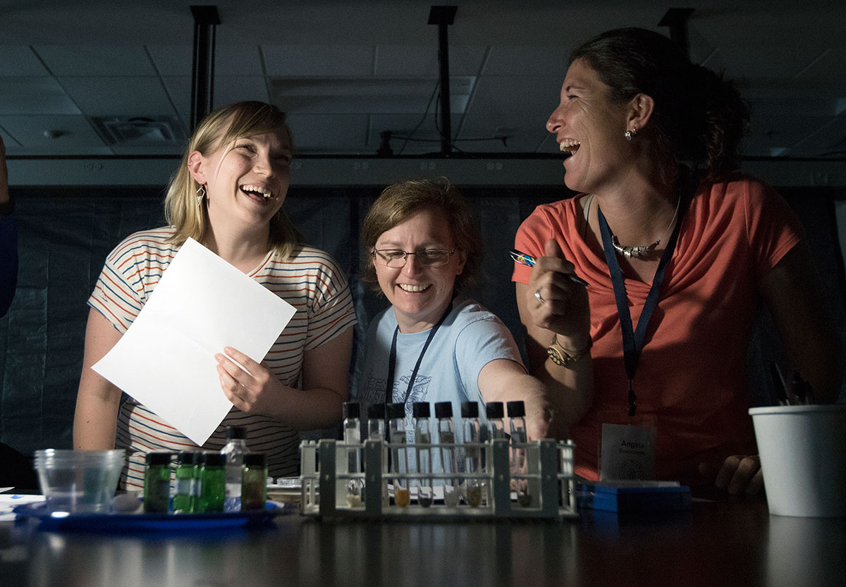 Kiki Contreras (from left), of Seattle Wash., Val Pumala, of Cameron, Wi., and Angela Gospodarek, of Gorham, Me., work together during an escape room activity Monday, June 5. The scholars were split into teams and used the microscopes they made earlier in the day to solve clues. (Photo by Brook Joyner)