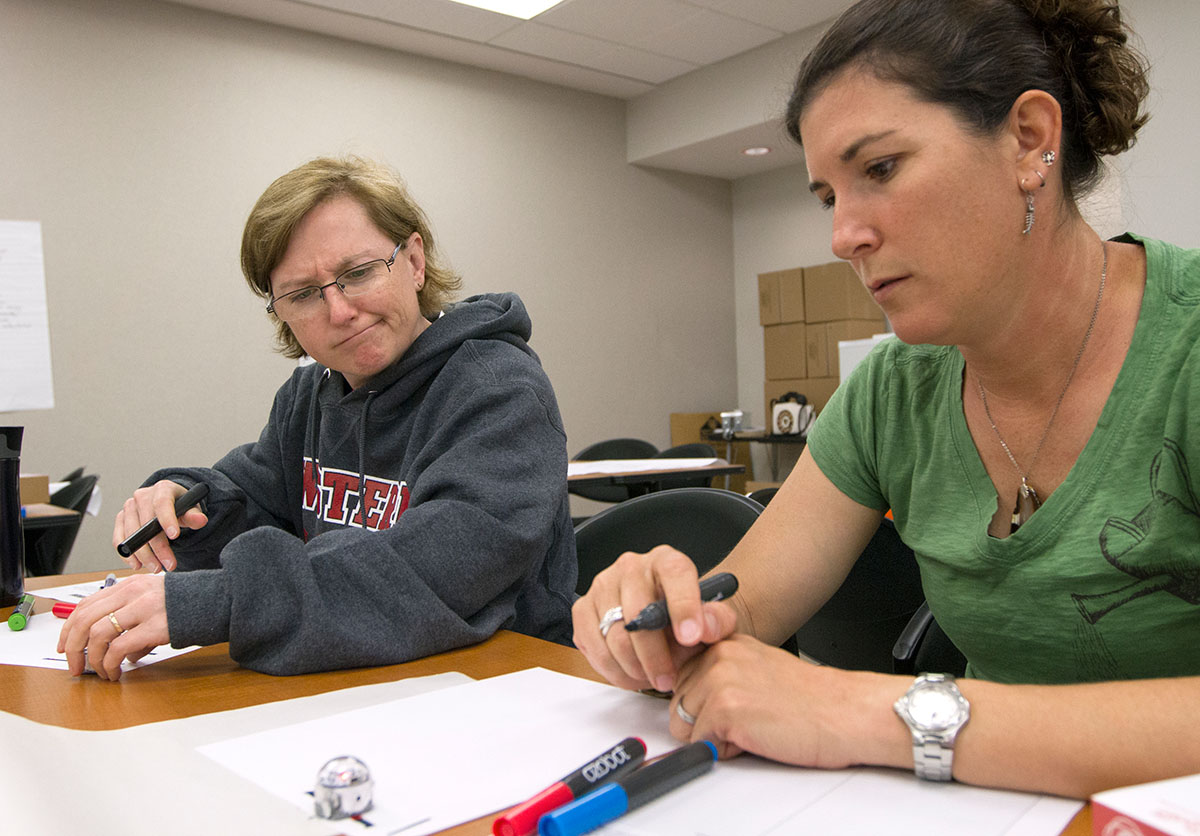 NSCF Scholars Val Pumala (left) from Cameron, Wi., and Angela Gospodarek from Gorham, Me., experiment with the codes used to control their Ozobot robots Thursday, June 8. The robots are coded using various sequences of colored marks. (Photo by Sam Oldenburg)
