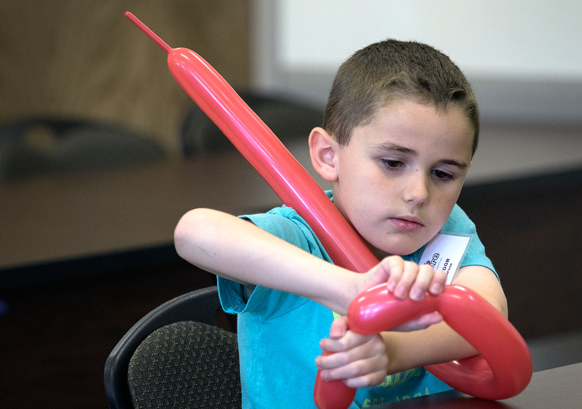 Braydon Thompson makes a balloon animal during Clowning at Camp Explore on Tuesday, June 6. Teacher Nick Wilkins helped the students turn their balloons into Dachshunds. (Photo by Brook Joyner)
