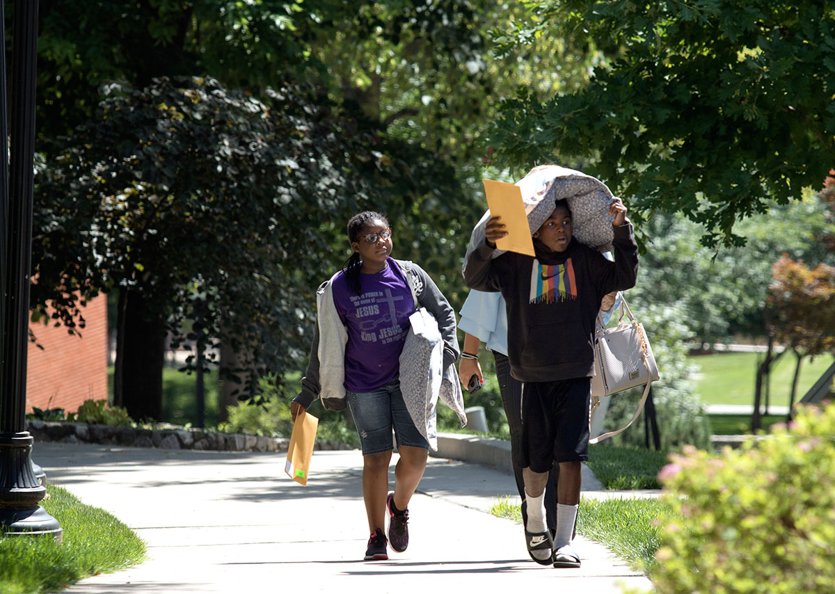 Kayla Wood (left) and Kenyan Wood, of Horse Cave, carry their belongings up the hill during move-in Sunday, June 11. After settling in,  campers met their counselor and the other people on their hall. (Photo by Brook Joyner)