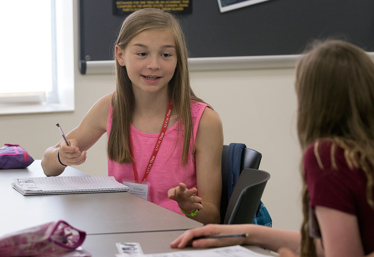 Hayden Tichenor of Henderson talks with a classmate about her story in Future Authors Tuesday, June 13. Students chose four images and wrote a short story based on the pictures. (Photo by Brook Joyner)