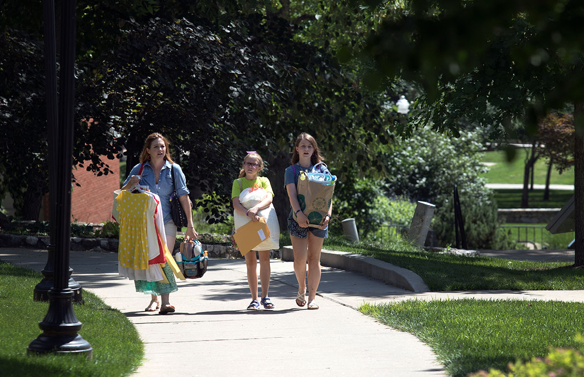 Mackenzie (left) and Emma Haupt of Columbia, Mo. carry their belongings to Florence Schneider Hall on the opening day of SCATS, Sunday, June 11. (Photo by Brook Joyner)