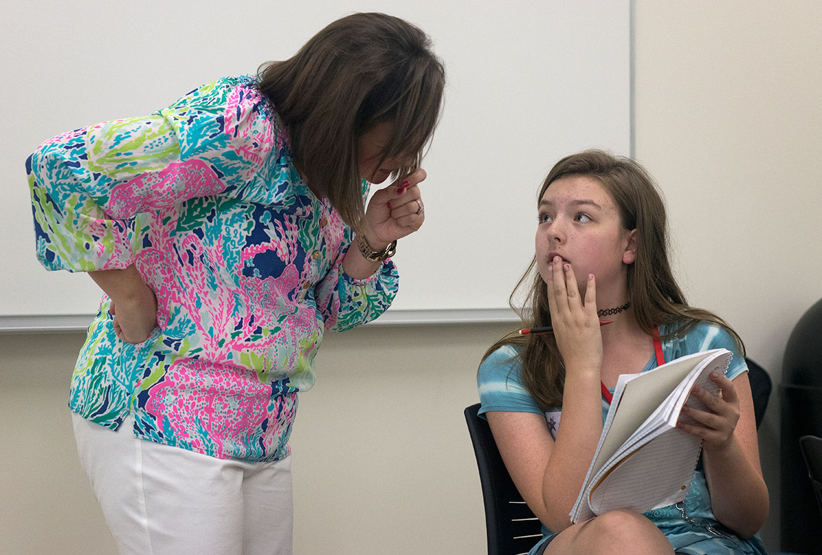 Kendall Pullum of Henderson shows her story to Future Authors teacher Lauren Griffing Thursday, June 15. Students were challenged to write a six-sentence paragraph without repeating any words. (Photo by Brook Joyner)