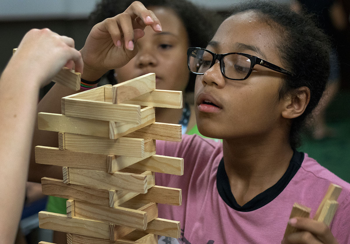 Bella Soares of Pearland, Texas, carefully places a building block on her tower during community time Tuesday, June 13. Bella worked with two other campers to build the tower which was more than four feet tall. (Photo by Brook Joyner)