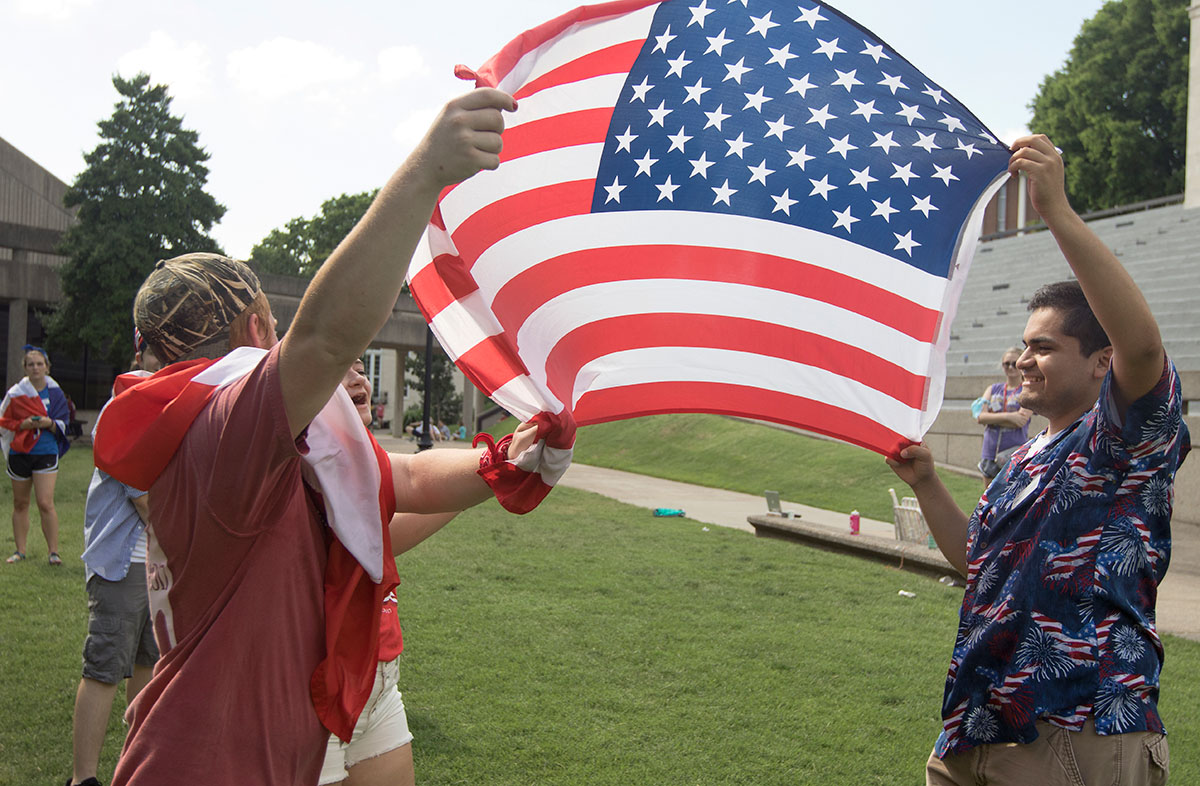Counselor Carlos Sierra (right) waves an American flag in the air with fellow counselors as team USA competes in tug-of-war Saturday, June 17. Each team consisted of one male and one female counselor group and chose a country to represent. (Photo by Brook Joyner)