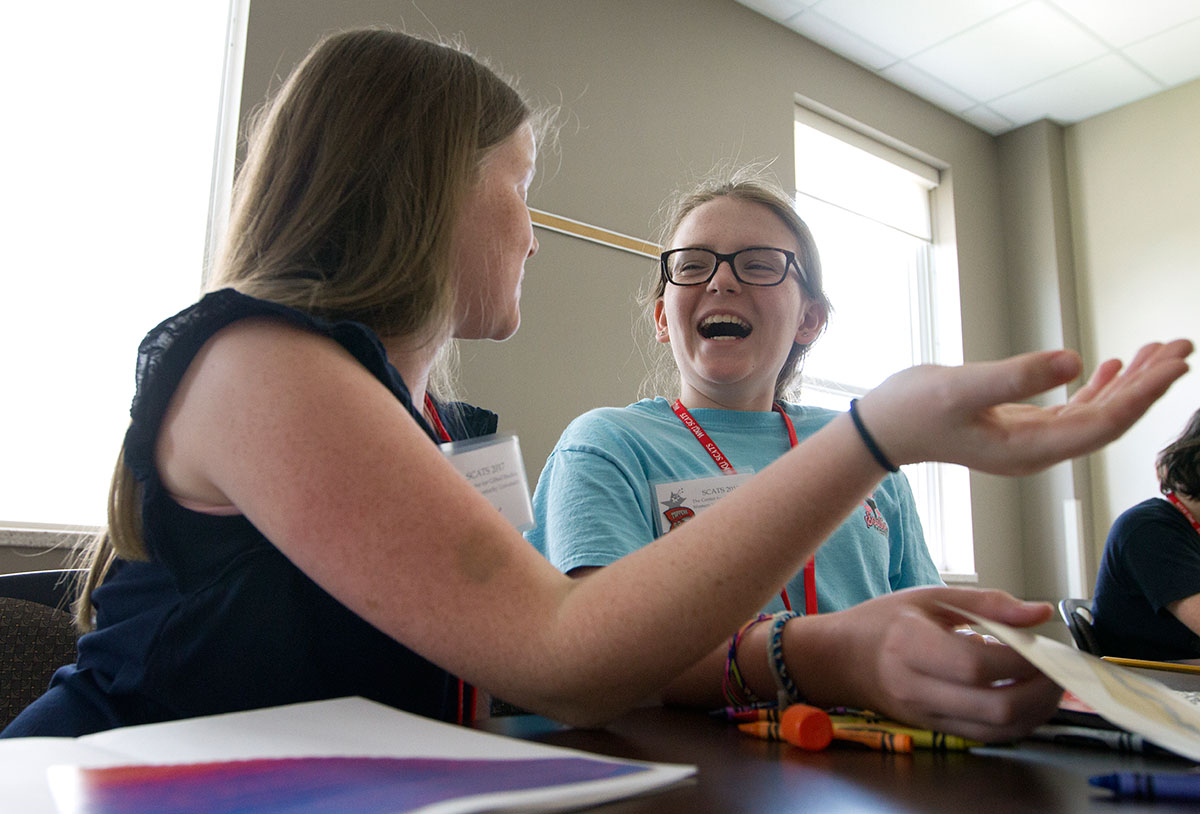 Emily Holland (left) of Louisville and Caroline Ardizzone of Fort Thomas discuss their projects in the Art of Graphic Design Monday, June 12. On the first day of class, students designed books about their interests. (Photo by Sam Oldenburg)